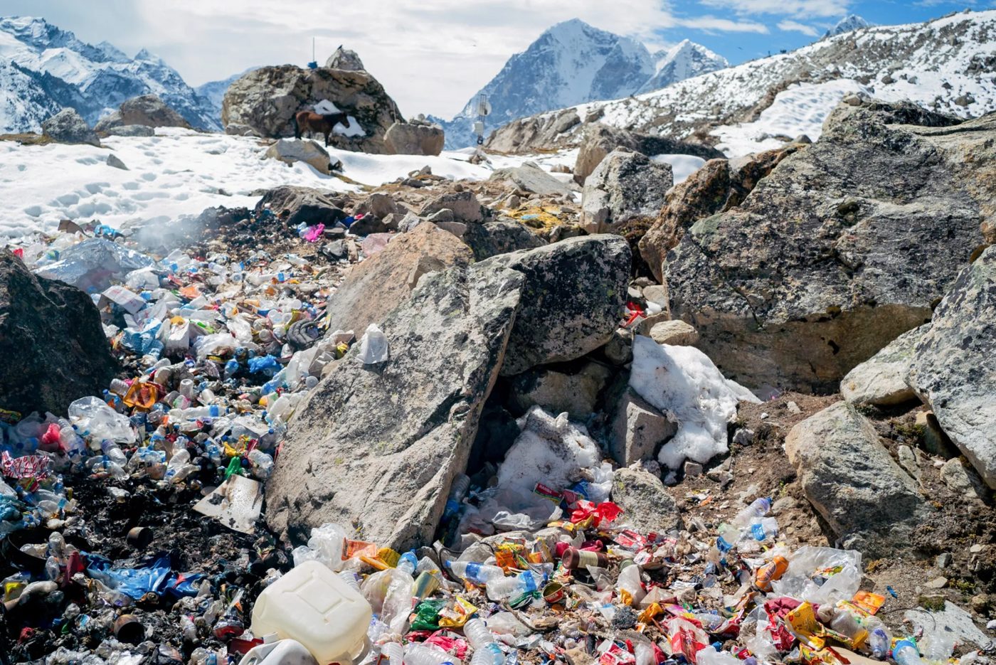 Piles of bottles and litter among rocks and snow below Everest